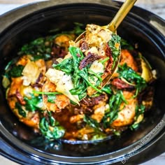 a wooden spoon full of food in a crock pot with spinach and other vegetables