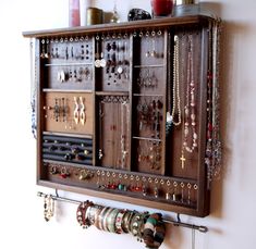 a wall mounted jewelry rack with lots of necklaces and earrings hanging on it's sides