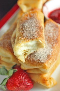 some strawberries are on a plate with crepes and powdered sugar in the middle