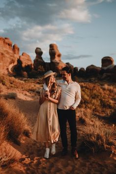 a man and woman are standing in the desert with rocks behind them, while holding each other's hands