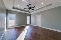 an empty living room with hard wood flooring and ceiling fan in the center of the room