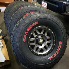 two black tires with red lettering on them sitting next to each other in a garage