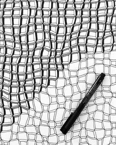 a pen sitting on top of a black and white netted surface with lines drawn across it