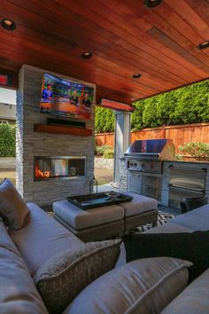 an outdoor living area with couches, television and grill