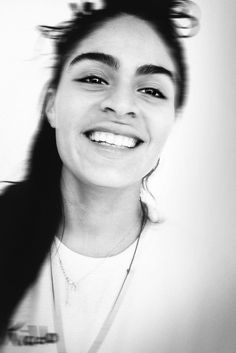 a woman with long hair smiling and wearing a white t - shirt in black and white