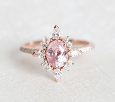 an engagement ring with a pink diamond surrounded by small white and rose cut diamonds on the band