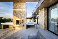 an outdoor living area with stone walls and floor to ceiling windows that overlook the landscape