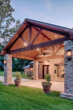 an outdoor covered patio with potted plants on the grass and lights hanging from the ceiling