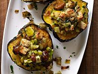 three stuffed acorns on a white plate topped with vegetables and meat toppings