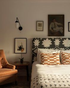 a bedroom with a bed, chair and pictures on the wall