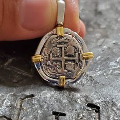 a person is holding a silver and gold necklace with a cross on it's side