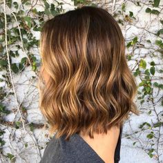 the back of a woman's head with wavy hair and brown to blonde highlights