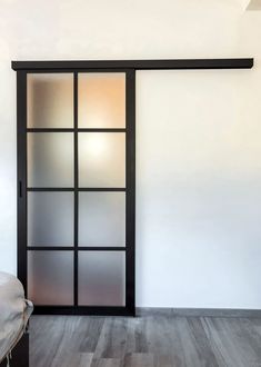 an empty room with white walls and wooden floors is seen in this image, the door has frosted glass panels