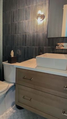 a white toilet sitting next to a sink in a bathroom under a mirror on top of a wooden cabinet