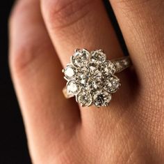 a woman's hand with a diamond ring on top of her finger and an engagement ring in the middle