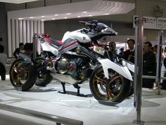 a motorcycle is on display at an event with people looking around the room and in the background