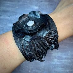 a close up of a person's arm wearing a black leather bracelet with flowers on it