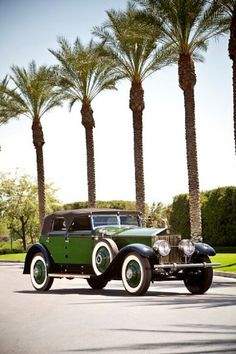 an old fashion car parked in front of palm trees on a street with no one around