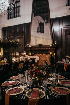 a dining room set up for an event with black and gold table cloths, place settings, and candles