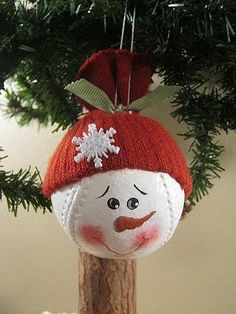 a snowman ornament hanging from a christmas tree with pine needles on it