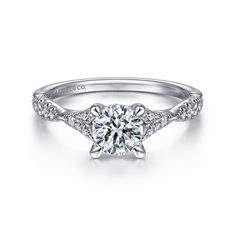 a white gold engagement ring with diamonds on the band and a round brilliant center stone