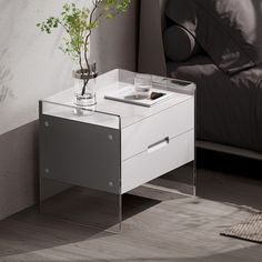 a small white table with a plant on it next to a bed in a room