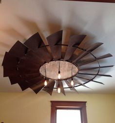 the ceiling fan is made from wood and has lights on top of it, along with two windows