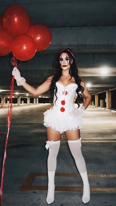 a woman dressed in white holding red balloons