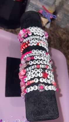 a stack of bracelets sitting on top of a pink tray next to other items