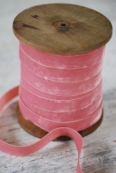 a spool of pink ribbon on a wooden table