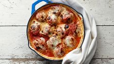 a close up of a pizza in a pan on a wooden table with a cloth