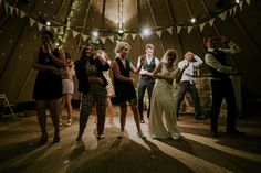 a group of people standing around each other in a room with lights on the ceiling