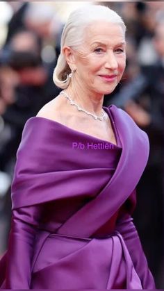 an older woman in a purple dress posing for the camera with her hand on her hip