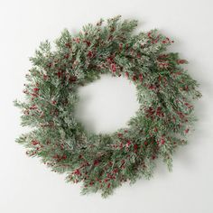 a wreath hanging on the wall with red berries and greenery around it's edges