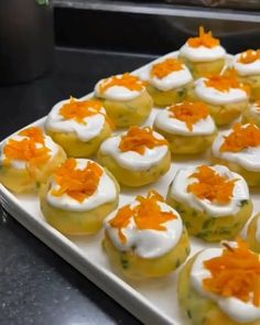 there are many small cupcakes with white frosting and orange flowers on them