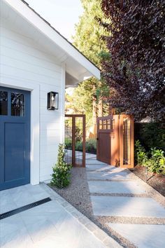 a white house with blue doors and landscaping