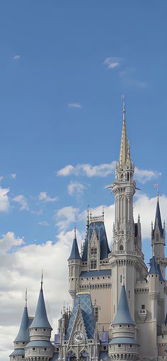 a large castle with many towers and spires on it's side against a cloudy blue sky