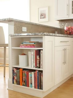 a kitchen with white cabinets and bookshelves filled with books on top of them