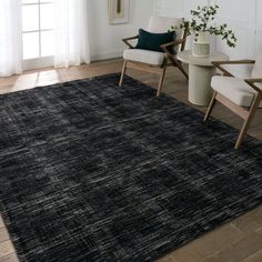 a black area rug in a living room with two chairs and a vase on the floor