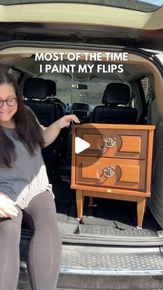 a woman sitting in the back of a van with her legs crossed and pointing at an end table