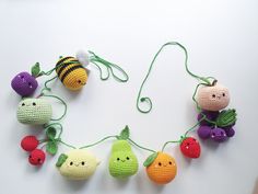 crocheted fruits and vegetables are hanging on a string, with faces drawn onto them