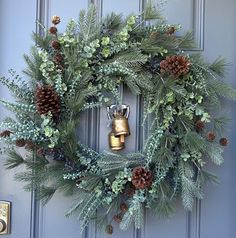 a wreath with pine cones and evergreens is hung on the front door by a golden bell