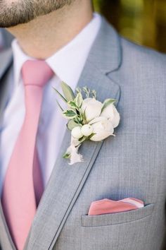 a man wearing a gray suit with pink tie and flower boutonniere on his lapel