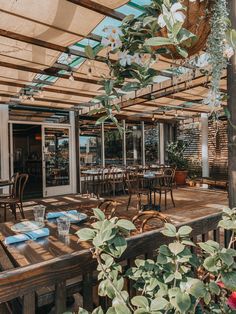 an outdoor dining area with wooden tables and chairs under a pergolated awning