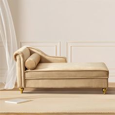 a beige chaise lounger sitting on top of a wooden floor next to a window