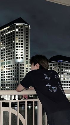 a man standing on top of a balcony next to a white fence and tall buildings