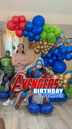 a woman standing in front of balloons with the words avengers birthday package on it and an image of hulk