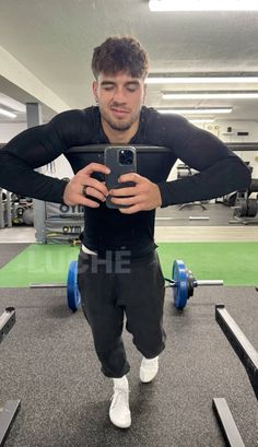 a man standing in the middle of a gym with his hands on his hips while holding a cell phone