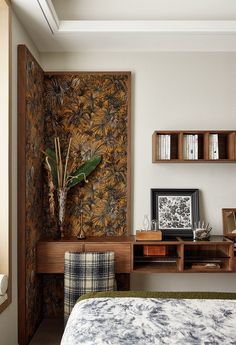 a bed room with a neatly made bed next to a wall mounted shelf and plant