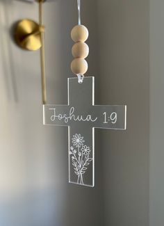 a glass cross hanging from the side of a wall with a name written on it